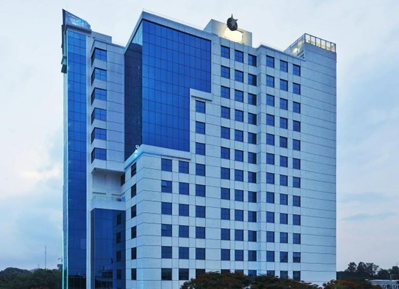 Exterior view of the glass-facade Prestige Khoday Tower under a soft sky.
