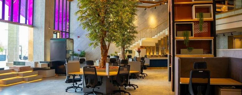 Spacious, light-filled lobby at Prince Turkey Al Awaal featuring indoor trees and shared workspaces.