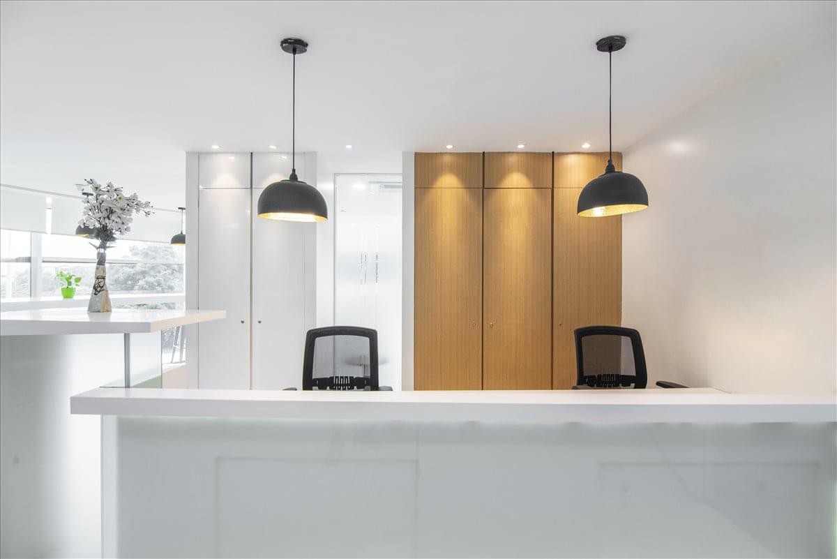 Bright reception desk at Sky One, Unit Nos. 101-104 with warm wood paneling and black pendant lights.