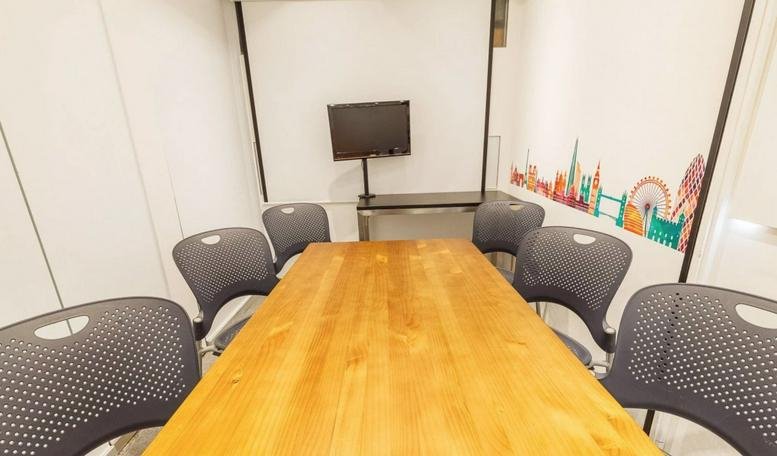 Professional meeting room at Radio City featuring a large wooden table and grey ergonomic chairs.