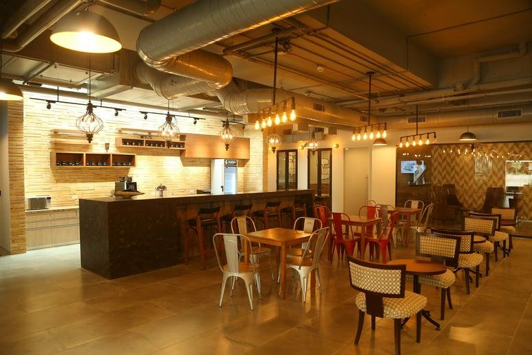 Spacious communal cafeteria at RMZ Ecoworld, Building 6A, featuring a coffee bar and varied seating.