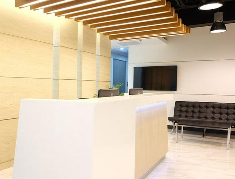 Modern reception area at 5th & 6th Floor Rockwell Business Center Tower 1 with wood slat ceiling and white desk.