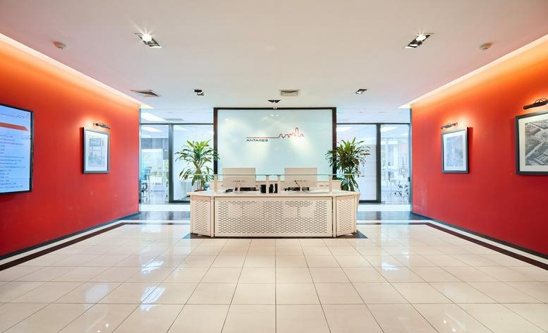 Spacious reception area with orange walls and a white marble desk at The RSU Tower.