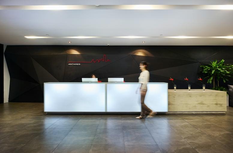 Wide-angle view of the modern, lit reception desk at The RSU Tower against a dark geometric wall.