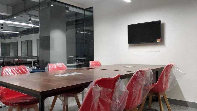 Modern meeting room at Sai Empire Above Poona Republic, Baner Road, Pune with a wood table and red chairs.