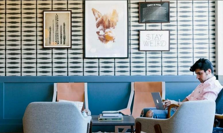 Spacious communal lounge at Samseong Station, 507 Teheran-ro with patterned wallpaper and artwork.