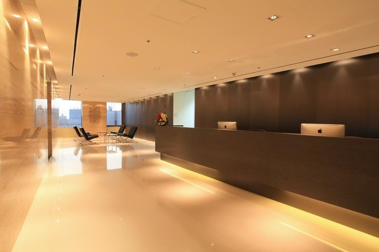 Sleek modern reception area with a long dark desk and warm recessed lighting.