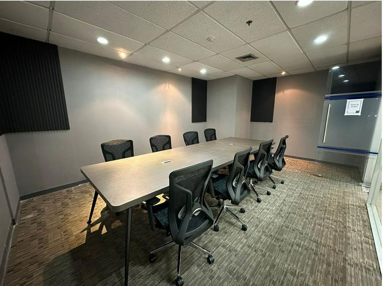 Spacious meeting room at Serm Mit Tower with a long grey table and black mesh chairs.