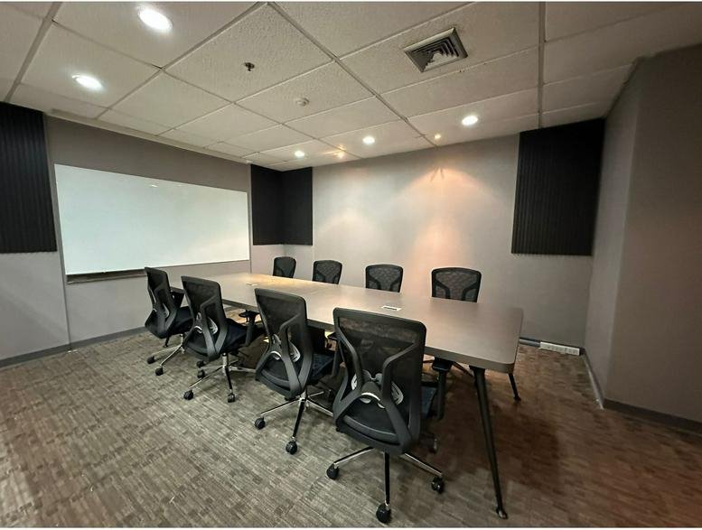 Spacious board room at Serm Mit Tower featuring a long table and black ergonomic chairs.