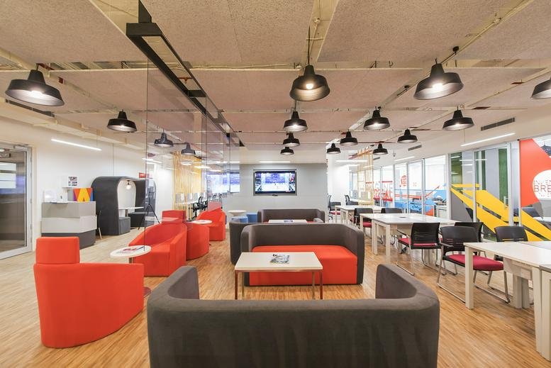 Vibrant communal lounge at Shanta Sriram Building, PSR Towers with red armchairs and warm pendant lighting.