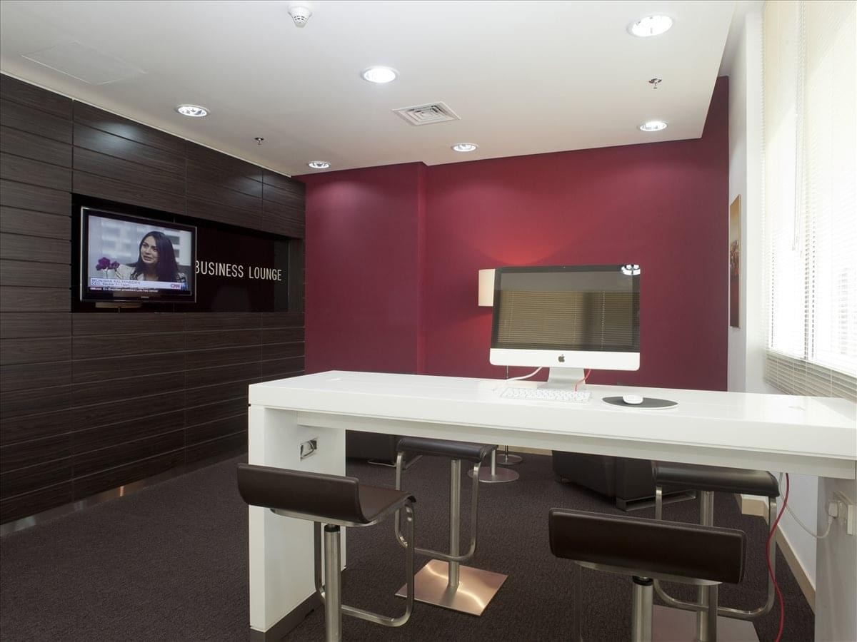 Modern business lounge with a high white counter, bar stools, and a feature wall in deep burgundy.