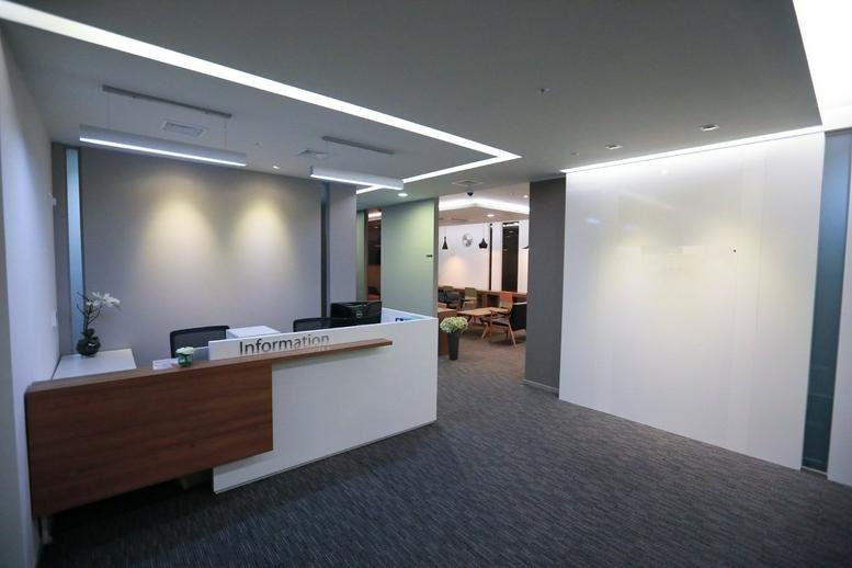 Modern reception area with a white front desk and warm wood paneling.