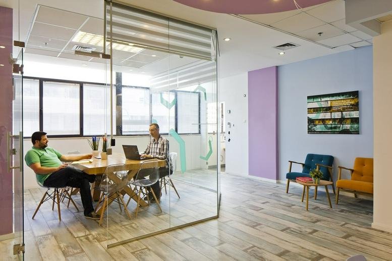 Modern interior of Shvil ha-Merets 2, Tel Aviv, Israel featuring a glass-enclosed meeting room and colorful lounge area.