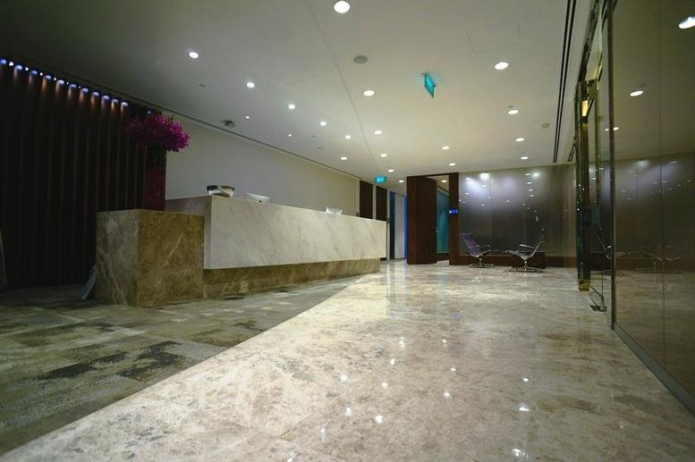 Modern reception area with a long marble desk and polished stone flooring.