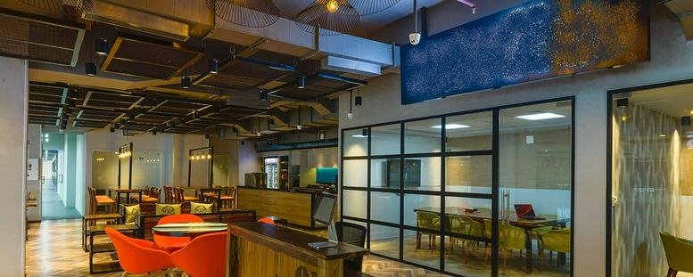 Wide view of the Skav 909 Building interior featuring bright orange seating and glass-walled meeting rooms.