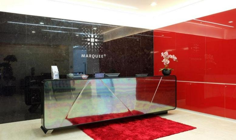 Modern reception area featuring a sleek reflective desk and a vibrant red feature wall.