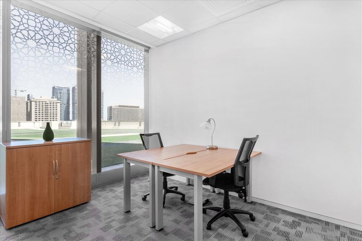 Bright private office at Standard Chartered Tower, Emaar Square, featuring a wooden desk and city views.