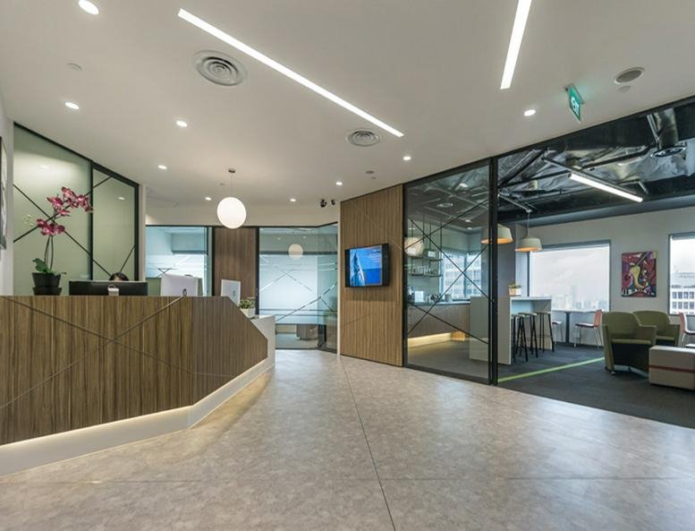 Modern reception area at Suntec Tower One with a wood-paneled desk and glass partitions.