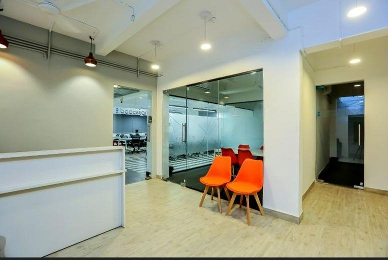 Reception area at Survery 65, Hindustan Estates, featuring a white desk and bright orange chairs.