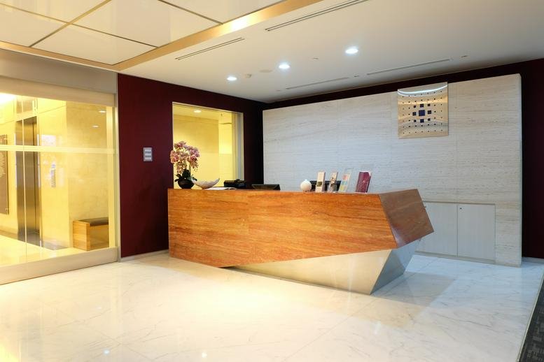Professional reception area featuring a warm wooden desk and a deep red accent wall.