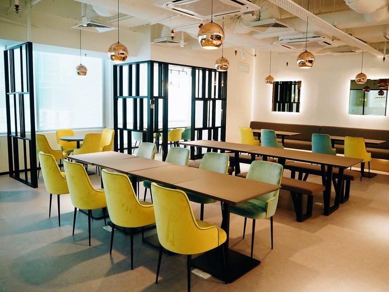 Spacious communal dining area at Level 27 Penthouse, The Centerpoint North Tower featuring yellow and green velvet chairs.