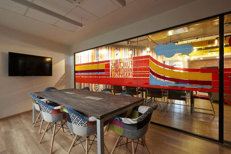 Meeting room at The Great Eastern Centre (GESCO) with a long wood table and vibrant graphic glass walls.