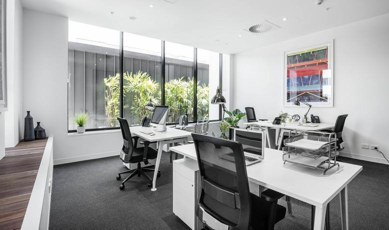 Spacious open-plan workspace at The Johnson, 477 Boundary Street, featuring floor-to-ceiling windows and greenery.