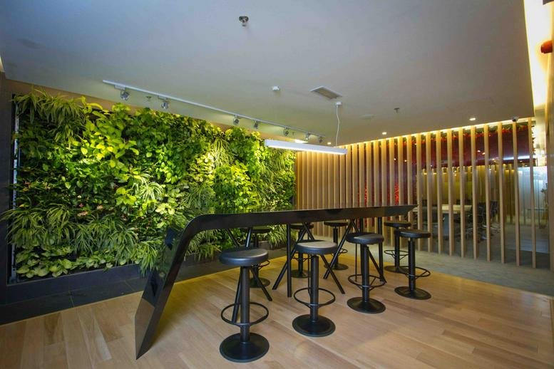 Lounge area featuring a long black high-top table against a lush vertical green wall.