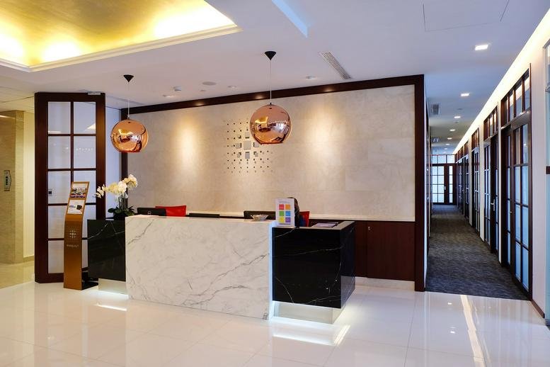 Marble and dark wood reception desk with warm pendant lighting.