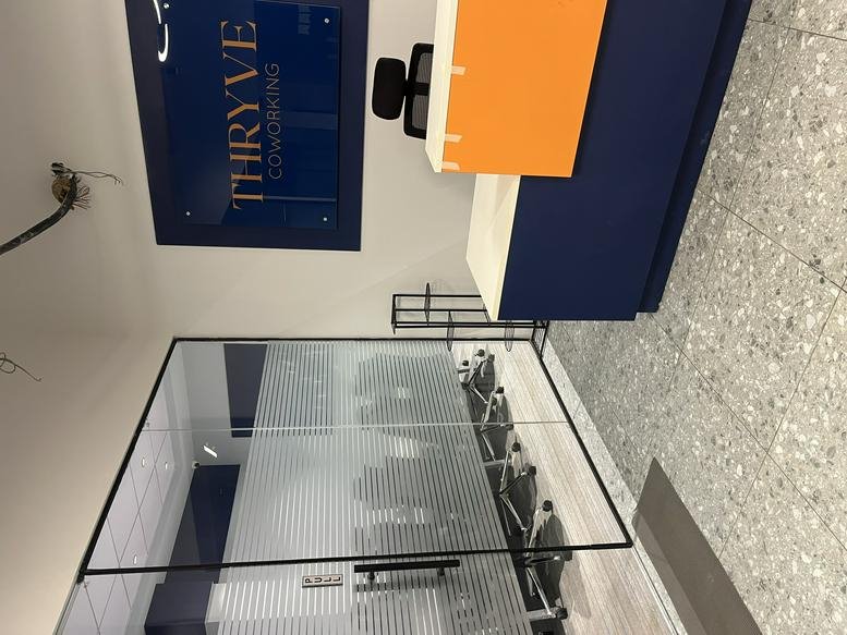 Reception area at Thryve Coworking, 18/1 Mathura Road, Faridabad, India with navy and orange branding.