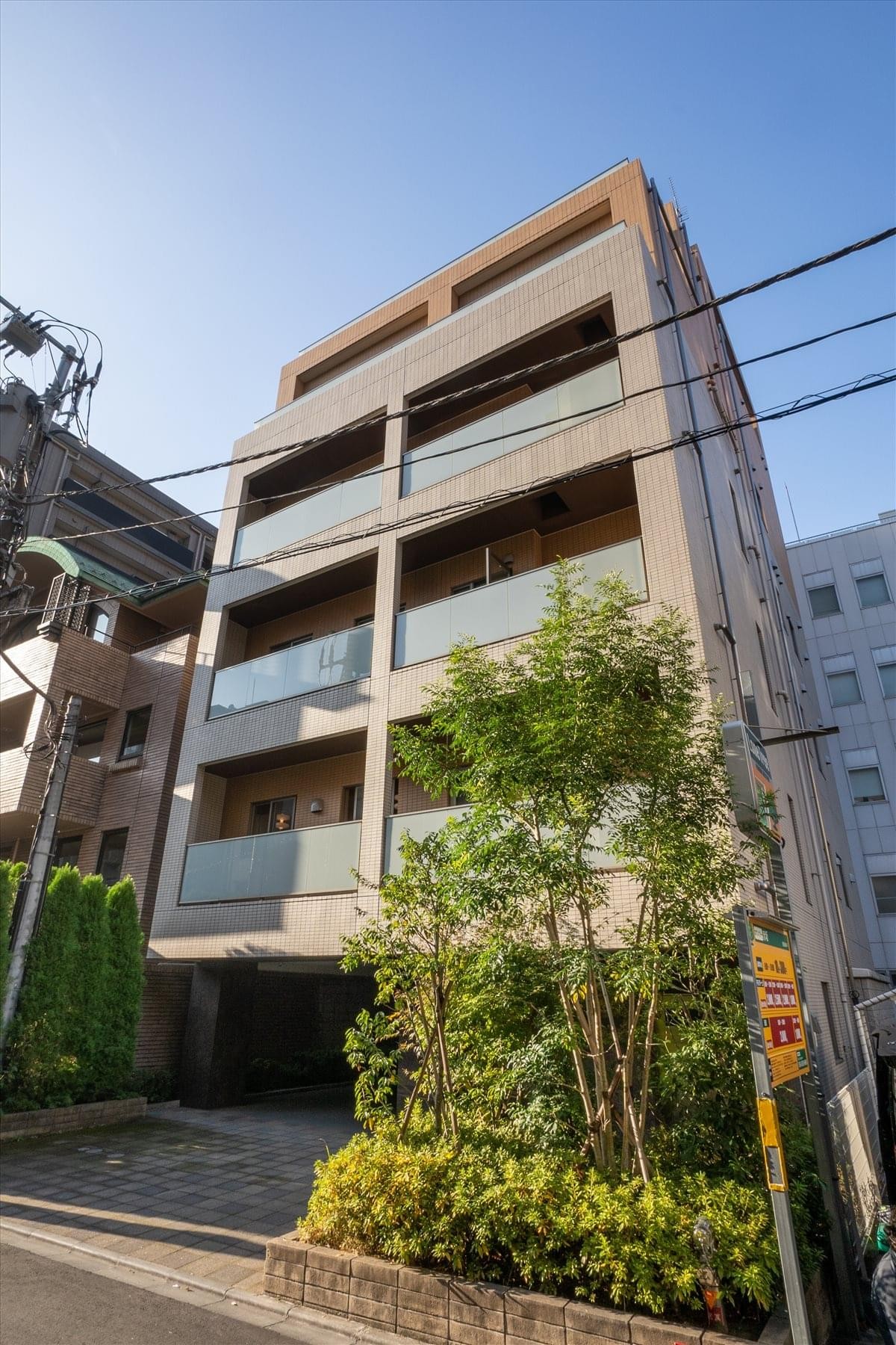 Exterior view of the modern tan-tiled Akasaka Buisiness Court building under a clear blue sky.