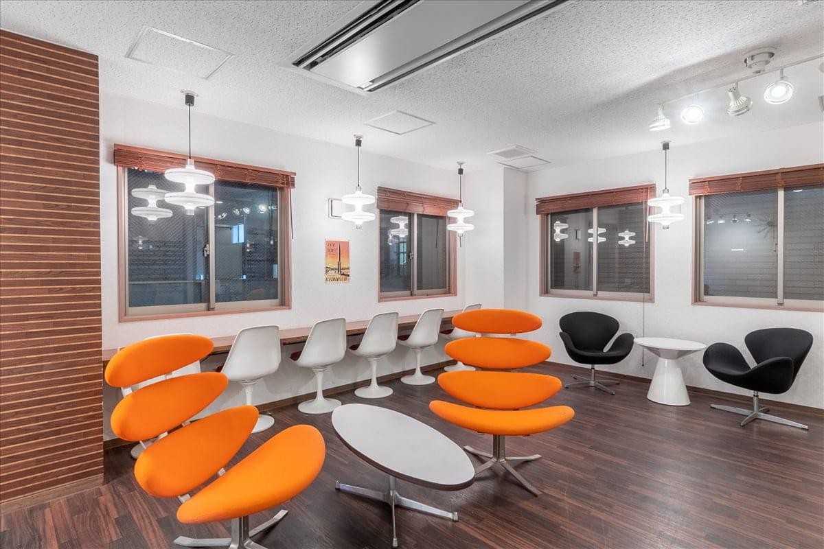 Communal breakout area with vibrant orange sculptural seating and a long window-facing counter.