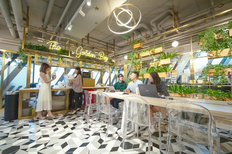 Vibrant communal lounge at Admiralty Centre, Tower 1, with a café bar, plants, and geometric flooring.