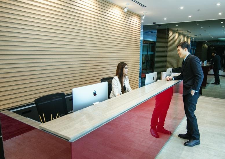 A modern reception desk with a wood-slatted feature wall and a person standing at the counter.