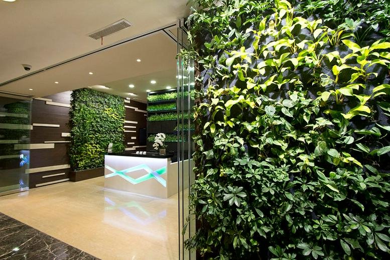 Modern lobby and reception area at Tower A, Kota Kasablanka with vibrant green living walls and sleek desk.
