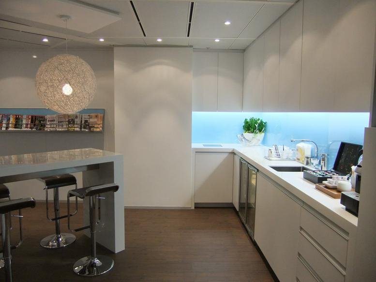 Modern communal kitchen and breakout area with a unique globe pendant light and blue backsplash.