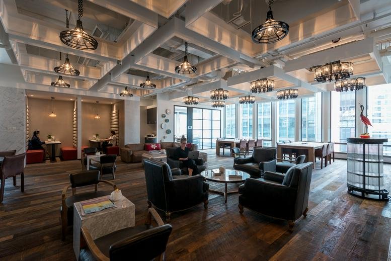 Spacious communal lounge at Two Chinachem Central with warm lighting, wood floors, and plush seating.