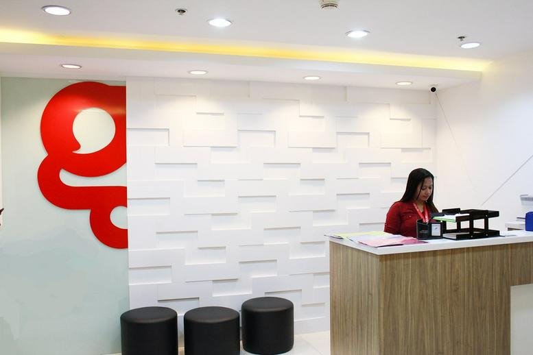 Reception area at UnionBank Plaza featuring a white textured feature wall, red logo, and wooden desk.