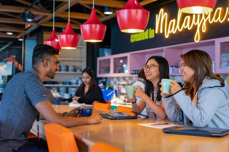 Vibrant cafe area at The Podium, Tower 3, UOA Business Park with red pendant lights and neon signage.