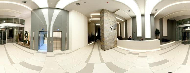 Spacious modern lobby with a curved reception desk and polished stone feature wall.