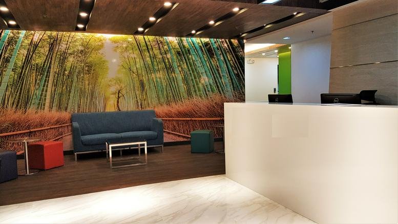 Warm reception area at V Corporate Center with a vibrant bamboo forest mural and blue sofa.