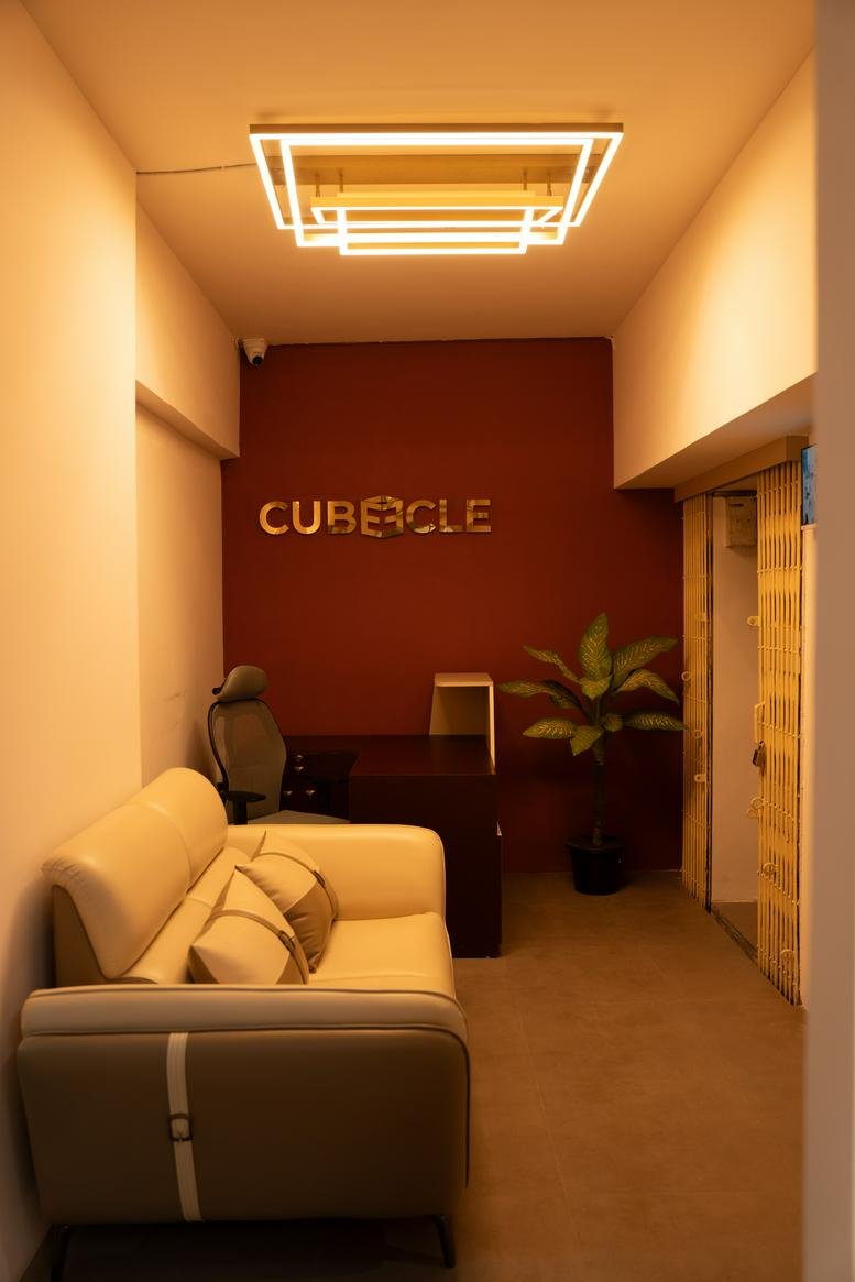 Warmly lit reception area at Vardhman Trade Centre, featuring a leather sofa and a branded feature wall.