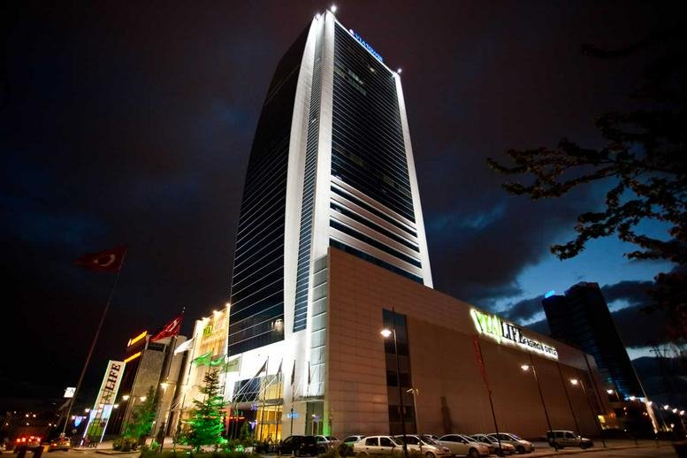 Exterior view of the illuminated Via Flat İş merkezi Nergiz sokak 7/2 skyscraper at night.