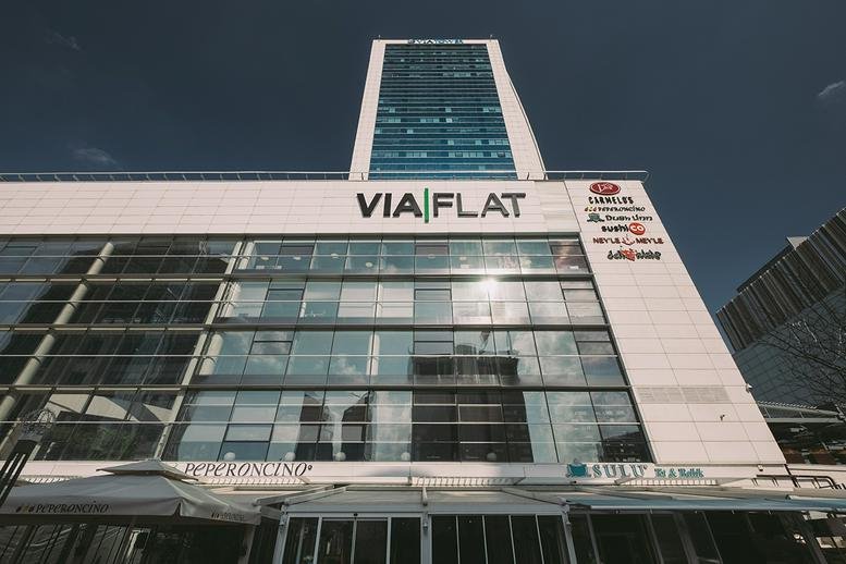 Modern glass facade of the building showcasing prominent signage under a clear sky.