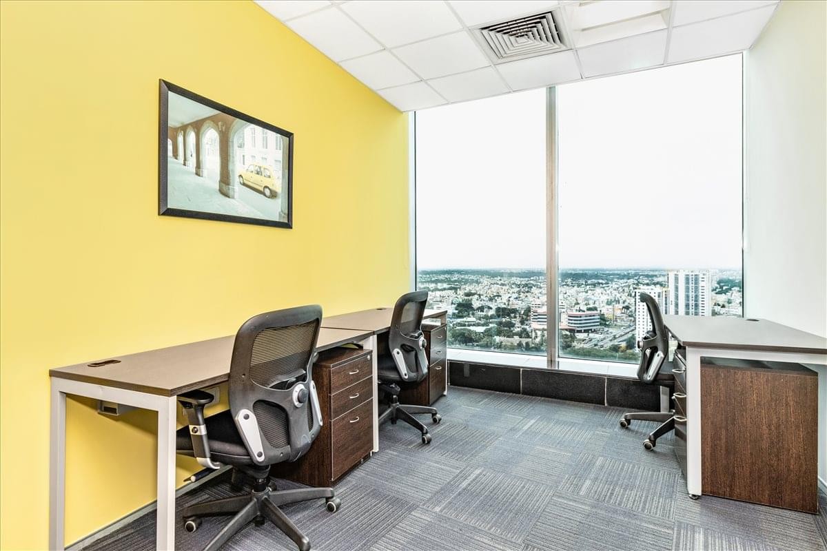 Spacious three-person office at World Trade Centre, Brigade Gateway with yellow feature wall and city views.