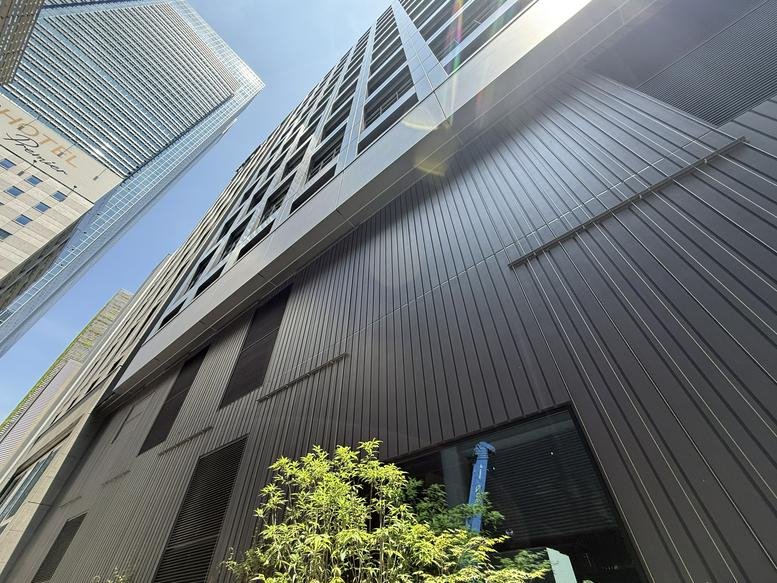 Low-angle exterior view of the modern glass and steel facade of the Yaesu Daibiru Building.