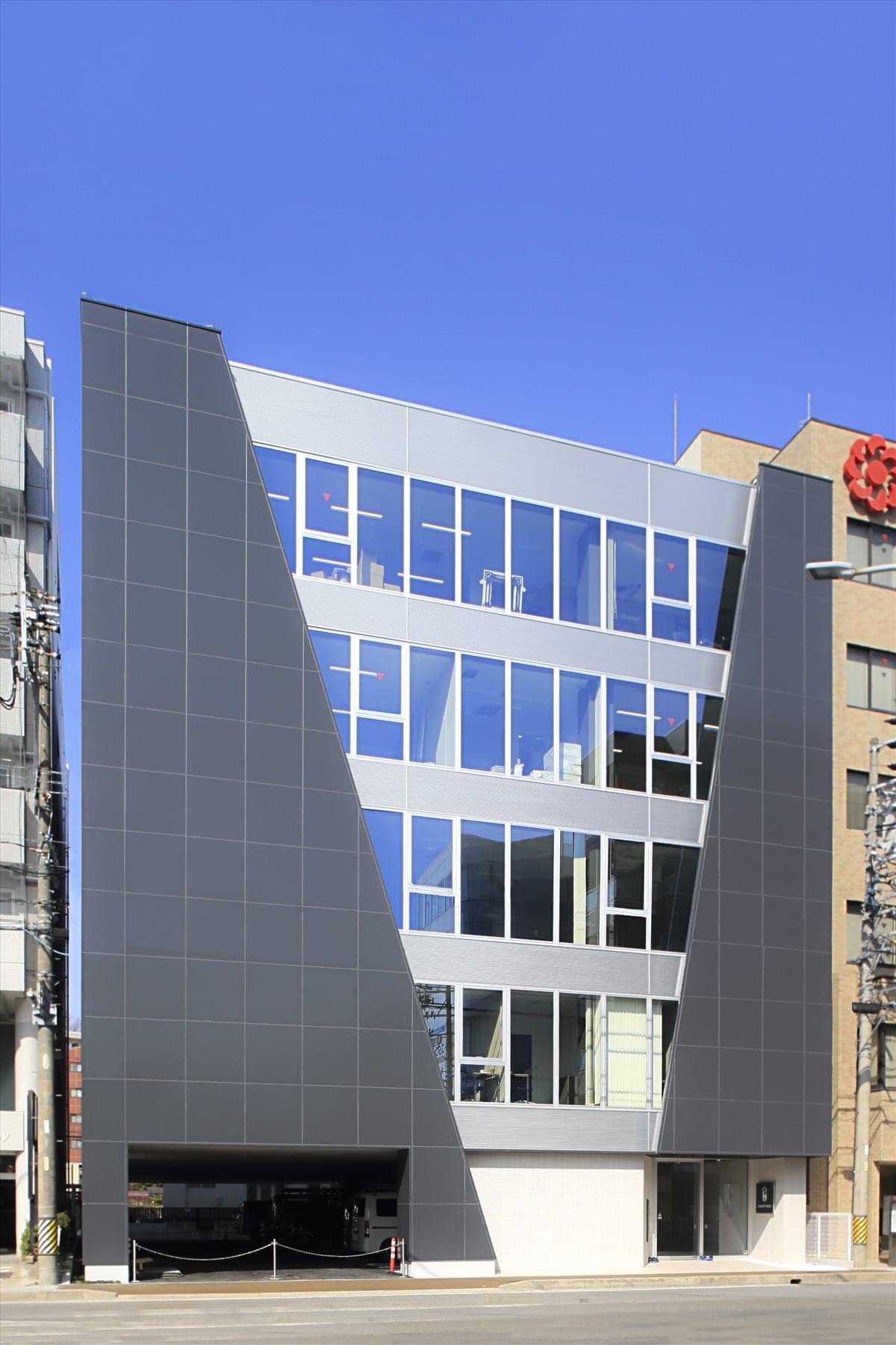 Exterior view of the contemporary Yamato Bldg featuring grey cladding and large glass windows.