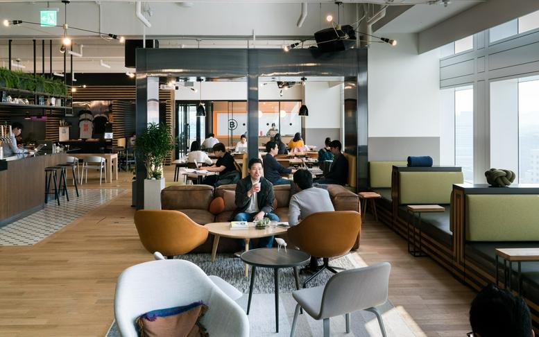 Spacious communal lounge at Yeouido Station, 83 Uisadaing-daero with mid-century modern furniture and cafe area.