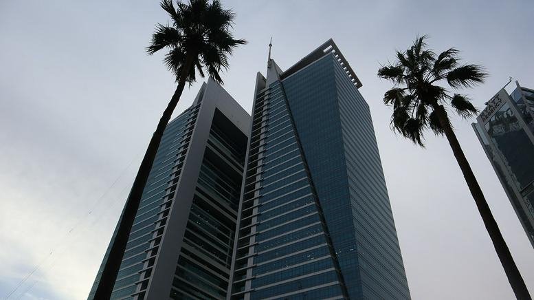 Exterior view of the modern glass skyscrapers at Olaya Towers with palm trees in the foreground.