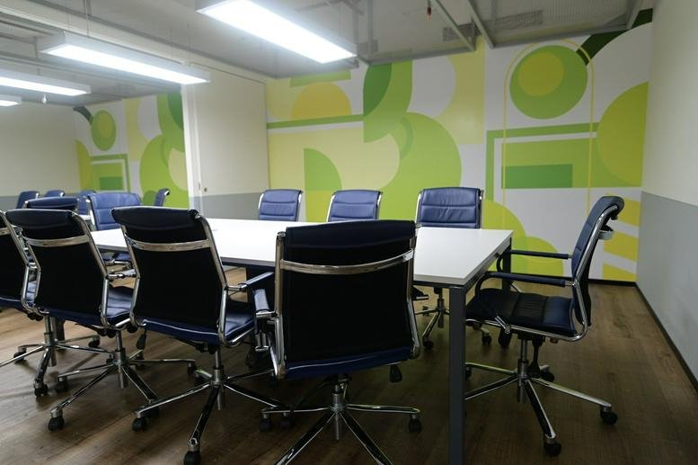 Modern conference room at Infra Futura with blue mesh chairs and vibrant green wall graphics.